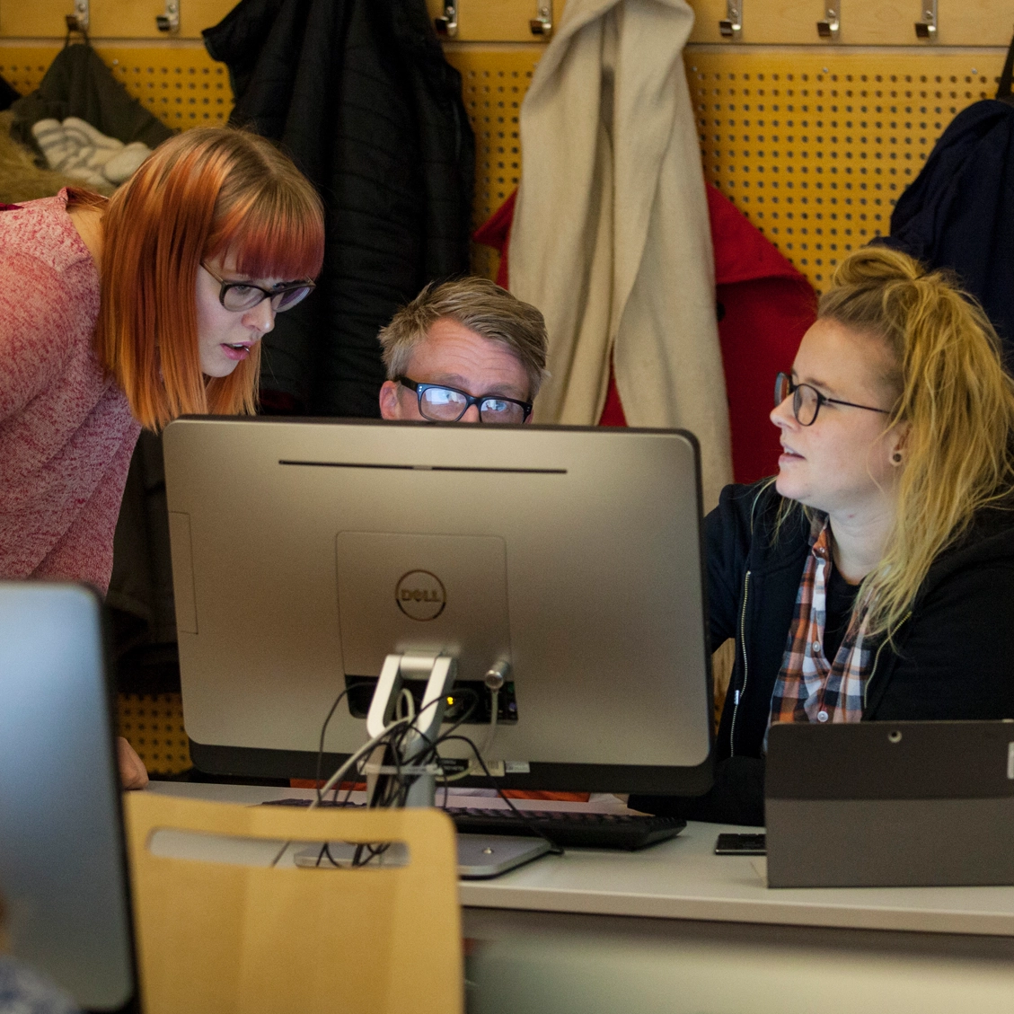 Tre personer framför en datorn.