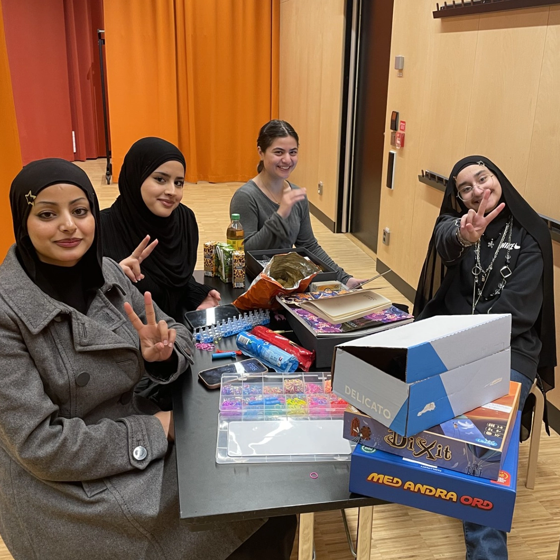 Fyra ungdomar sitter vid ett bord leende mot kameran.