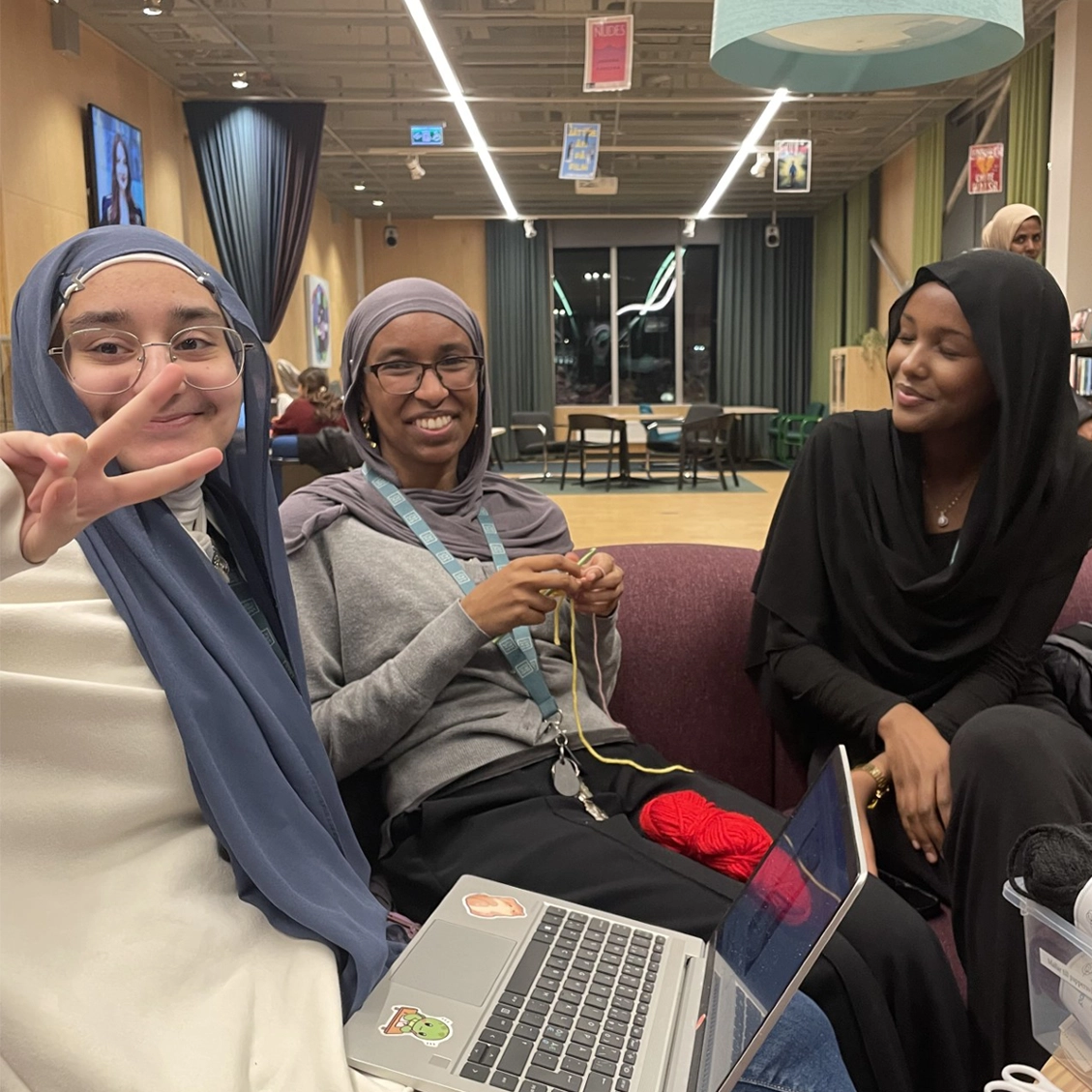 Tre ungdomar sitter på en soffa och ler mot kameran.