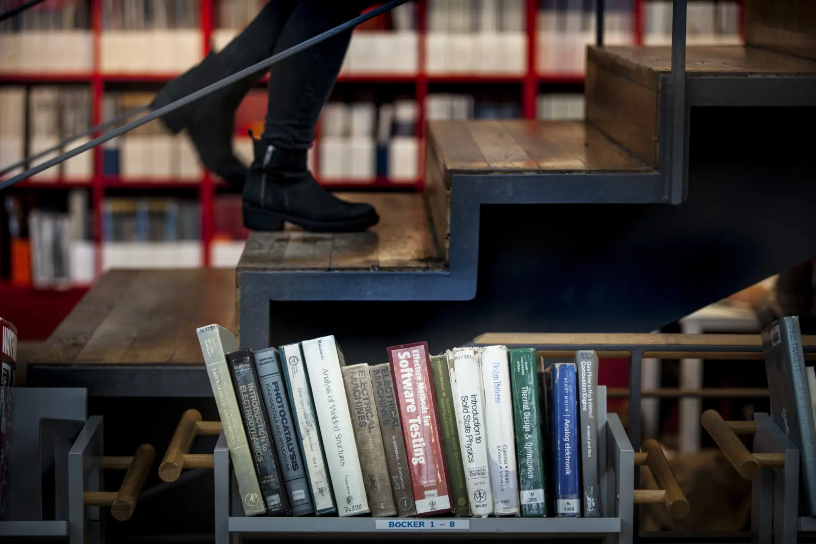 Bild på flera böcker i rad på en bokvagn, med en trappa i bakgrunden.