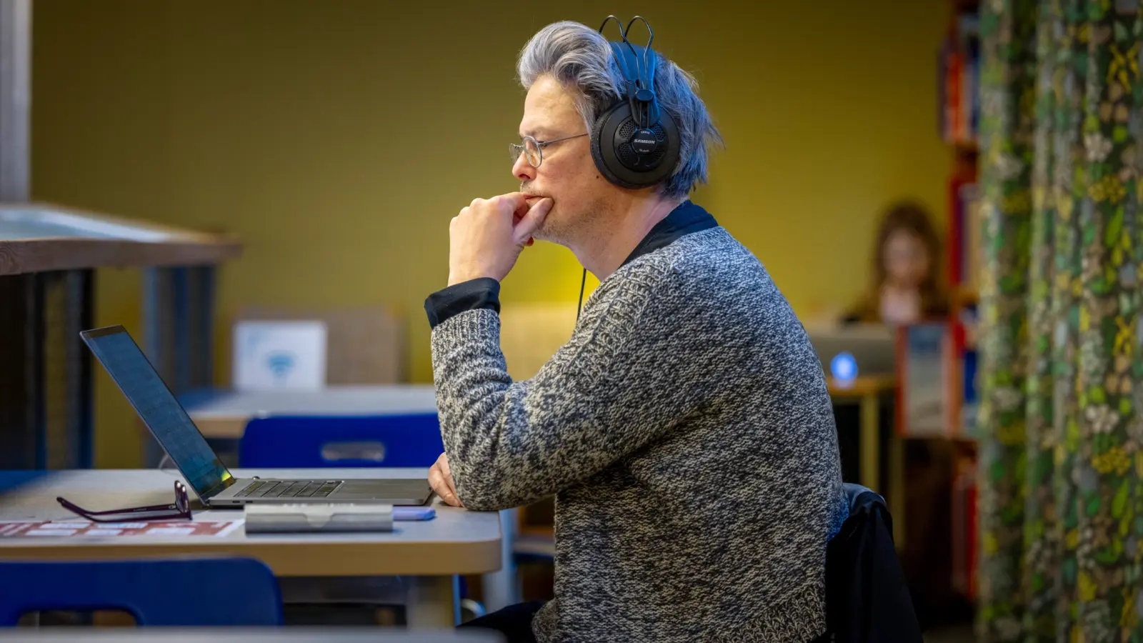 Man som sitter framför dator på ett bibliotek.